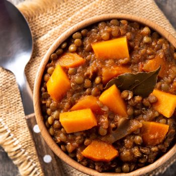 Lentil stew ragout with pumpkin and carrot in bowl on wooden table